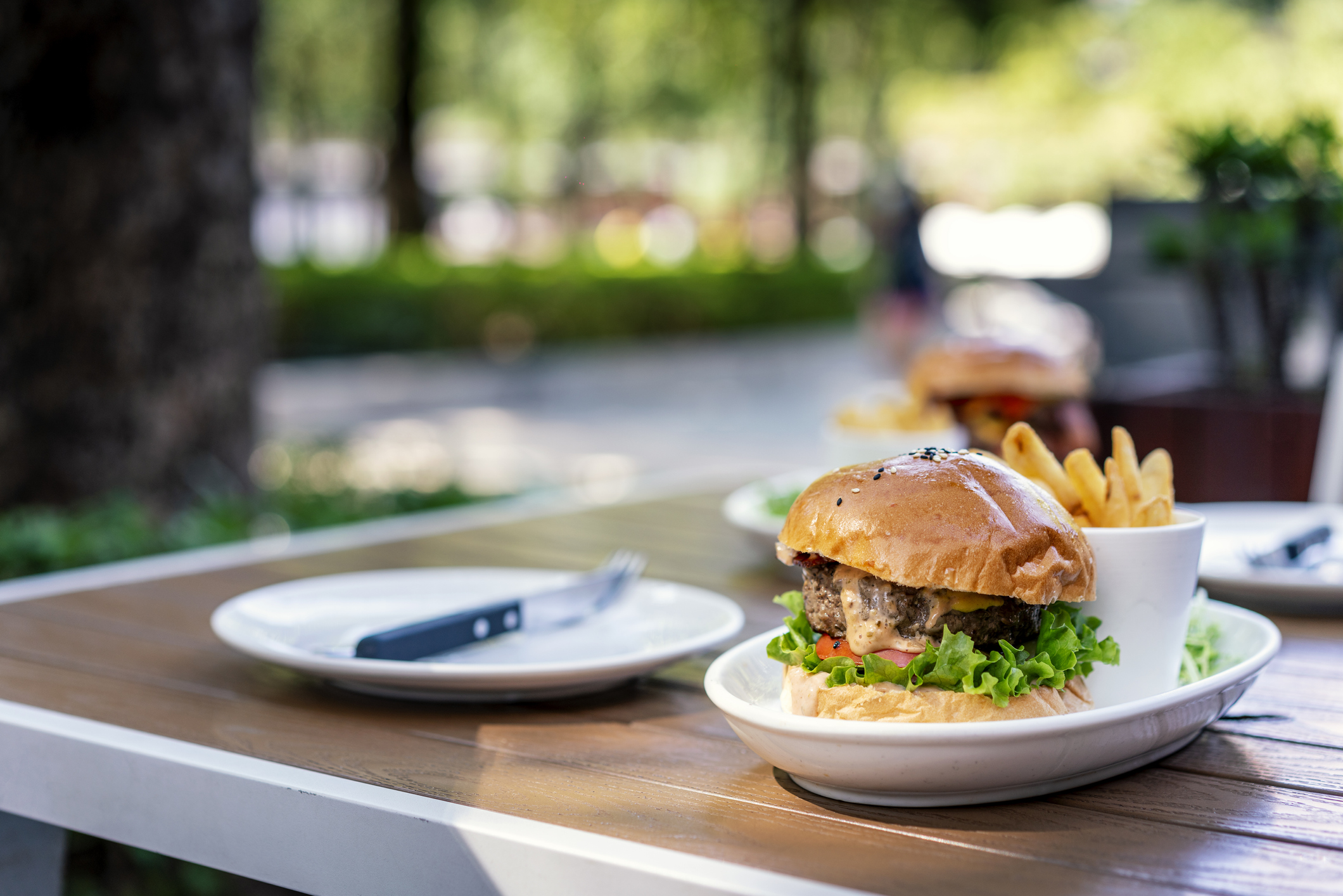 A hamburger and fries on an outdoor restaurant table.